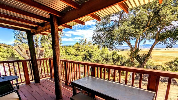 A wooden deck with a table and bench, overlooking a scenic landscape with trees and a distant view. - # 3. Howling Wolf's Lair - Studio W/ Fireplace (Pet Free) (Santa Ysabel)