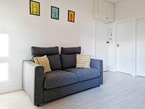 Relax in this stylish living room with a sofa, two pillows, and three framed artworks.
