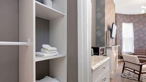 A modern bathroom with a built-in shower, a toilet, and a sink. There is a towel rack with folded towels and a shower curtain.