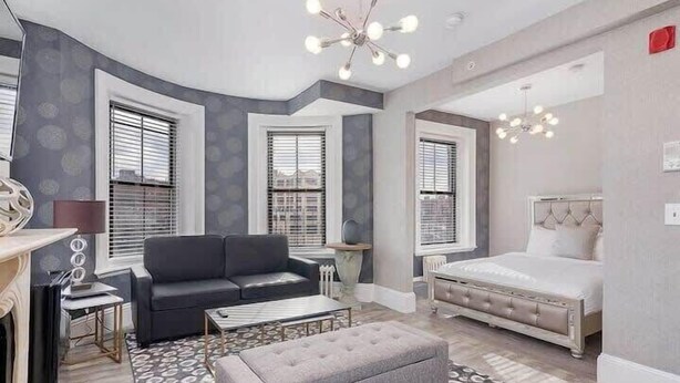 A modern bedroom with a bed, a grey sofa, and a coffee table.
