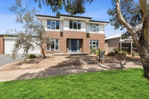 A two-story house with a brick facade, a front door, and a driveway. - Seahaze Retreat | Spacious Family Coastal Haven (Torquay)