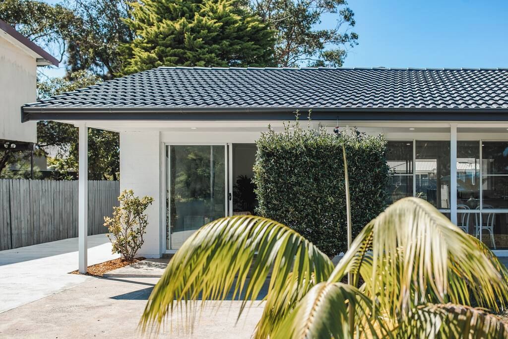 Une maison moderne avec un toit en tuiles, de grandes fenêtres et une terrasse couverte.