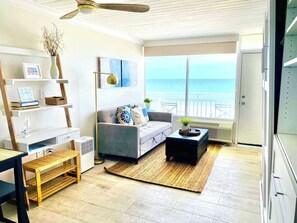 A living room with a sofa, coffee table, and a view of the ocean. - Sugar Sands - Ocean front at Symphony Beach Club ! (Ormond Beach)