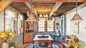 Un comedor rústico con una mesa de madera, sillas y lámparas colgantes.