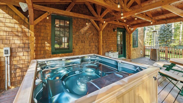 Una cabaña de madera con jacuzzi y una terraza.
