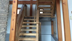 Un escalier en bois mène à une mezzanine dotée d’une fenêtre donnant sur l’intérieur.