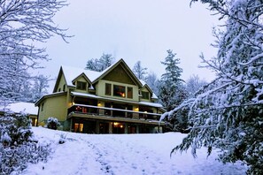 Un gran edificio de varios pisos con un balcón destacado y un paisaje cubierto de nieve.
