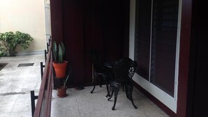 A covered outdoor seating area with a table and chairs, a potted plant, and a sliding glass door. - Oxford manner Our Gem  (Kingston)