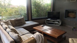 A living room with a sofa, a coffee table, a TV, and a fireplace. - A break for two in a detached villa with SPA (Sainte-Anastasie)