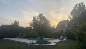 A backyard with a swimming pool, surrounded by trees and a stone wall. - A break for two in a detached villa with SPA (Sainte-Anastasie)