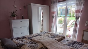 Un dormitorio con cama, armario, planta en maceta y vistas al exterior.