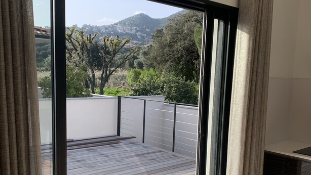 A modern room with a large sliding glass door leading to a wooden deck. - Magnificent villa with private pool (monticello)