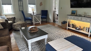 Un salon avec un canapé, une table basse, un téléviseur et une bibliothèque.