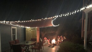 Une terrasse extérieure dotée d’un foyer, de guirlandes lumineuses et de sièges.