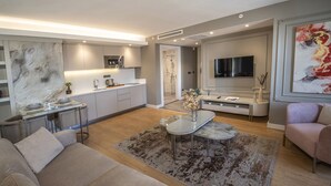A modern living room with a sofa, a coffee table, and a dining area with a table set for two. - Valente Suites & Hotel (Istanbul)