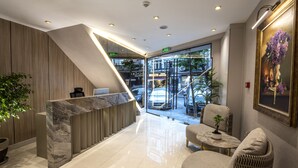 A modern lobby with a marble reception desk, seating area, and a large window offering a view of the street. - Valente Suites & Hotel (Istanbul)