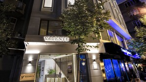 A modern building with a prominent 'Valente' sign at the entrance, featuring a glass facade and a staircase leading to the entrance. - Valente Suites & Hotel (Istanbul)