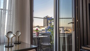 A modern room with a glass door leading to a balcony, a small table with chairs, and a potted plant. - Valente Suites & Hotel (Istanbul)