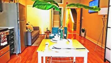 A compact living space with a kitchen, dining area, and a staircase leading to an upper level.