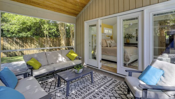 Un espacio de patio techado con sofá, sillas y una mesa de centro.