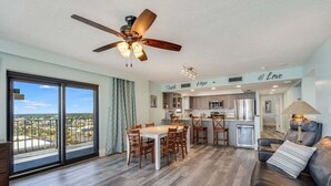A spacious living area with a dining table, a sofa, and a ceiling fan.
