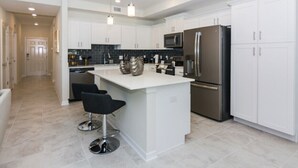 A modern kitchen with white cabinets, stainless steel appliances, and a central island with bar stools. - Spacious Apartment 2BR/2BA • Near Disney • Storey Lake Resort [SL47317] (Kissimmee)