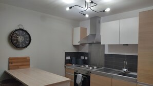 A modern kitchen with a central island, a built-in oven, and a stainless steel range hood. - Fantastic Centrally Located 1 bed Apartment (Liverpool)