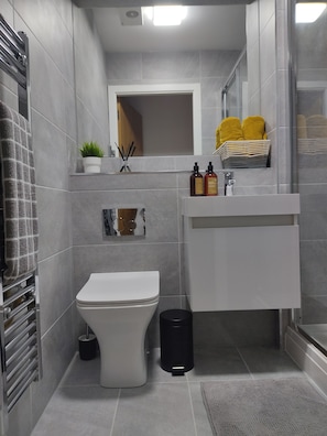 Ein modernes Badezimmer mit Toilette, Waschbecken und Duschbereich.
