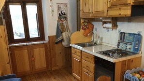 A compact kitchen with wooden cabinets, a sink, and a stove. - Monterosa winter vacation home (Gressonay Saint Jean)