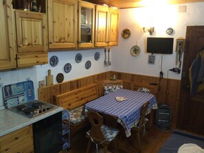 Eine kleine Küche mit Holzausstattung, einem Esstisch mit blauer Tischdecke und einem Herd.