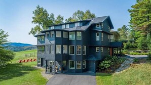 A two-story house with a dark blue exterior, multiple windows, and a front porch.