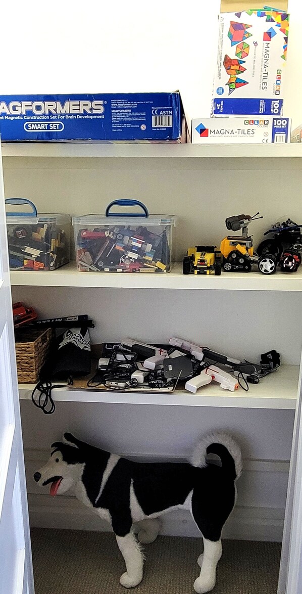 Un estante con coches de juguete, un perro y cajas de juegos de construcción.