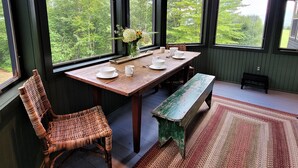 A dining area with a wooden table set for four, a bench, and a wicker chair.