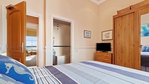 Une chambre d’hôtel avec un lit, une télévision, une armoire et une salle de bain visible à travers une porte ouverte.
