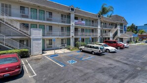 A multi-story motel with a 'Hiring Housekeepers' sign, parking spaces, and a staircase leading to the entrance. - Beachside Inn (Anaheim)