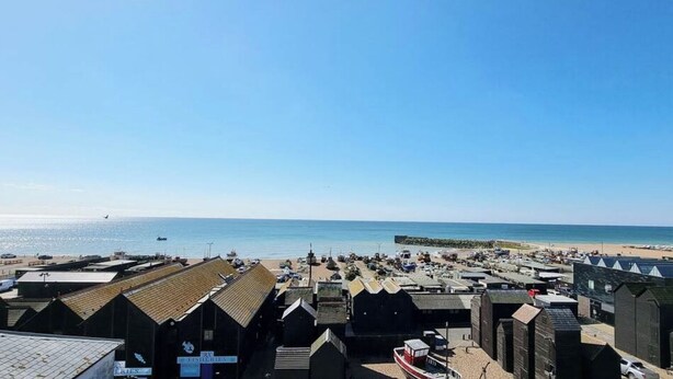 A coastal town with a beach, fishing huts, and a clear blue sky. - Charming Old Town Cottage With Modern Features (Hastings)