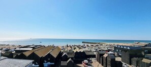 Een kustplaatsje met een strand, vissershutten en een helderblauwe lucht.