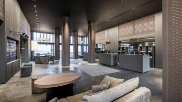 Un vestíbulo amplio con una zona de estar central, un mostrador de recepción y una cocina.