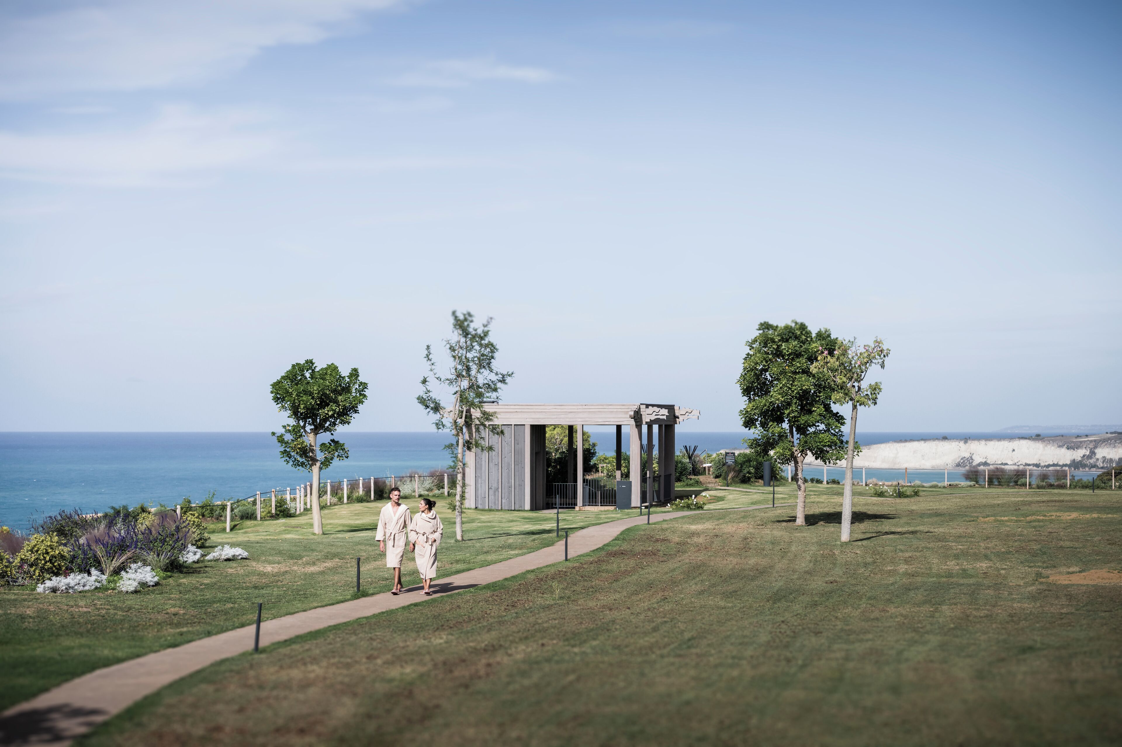 A pathway leading to a pavilion with a view of the ocean.