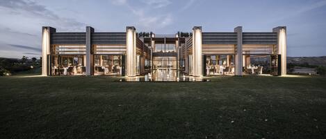 Un edificio moderno con fachada simétrica, grandes ventanales y un espacio abierto central.