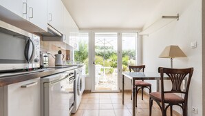 A kitchen with a dining area, a washing machine, and a view of the garden through the glass door. - Close to beaches (300 m) (plozevet)