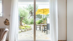 A room with a sliding glass door leading to an outdoor patio area with a yellow umbrella, a dining table, and chairs. - Close to beaches (300 m) (plozevet)