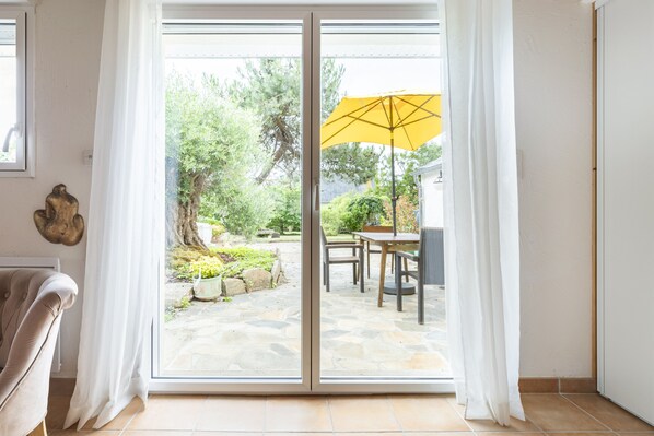 A room with a sliding glass door leading to an outdoor patio area with a yellow umbrella, a dining table, and chairs.