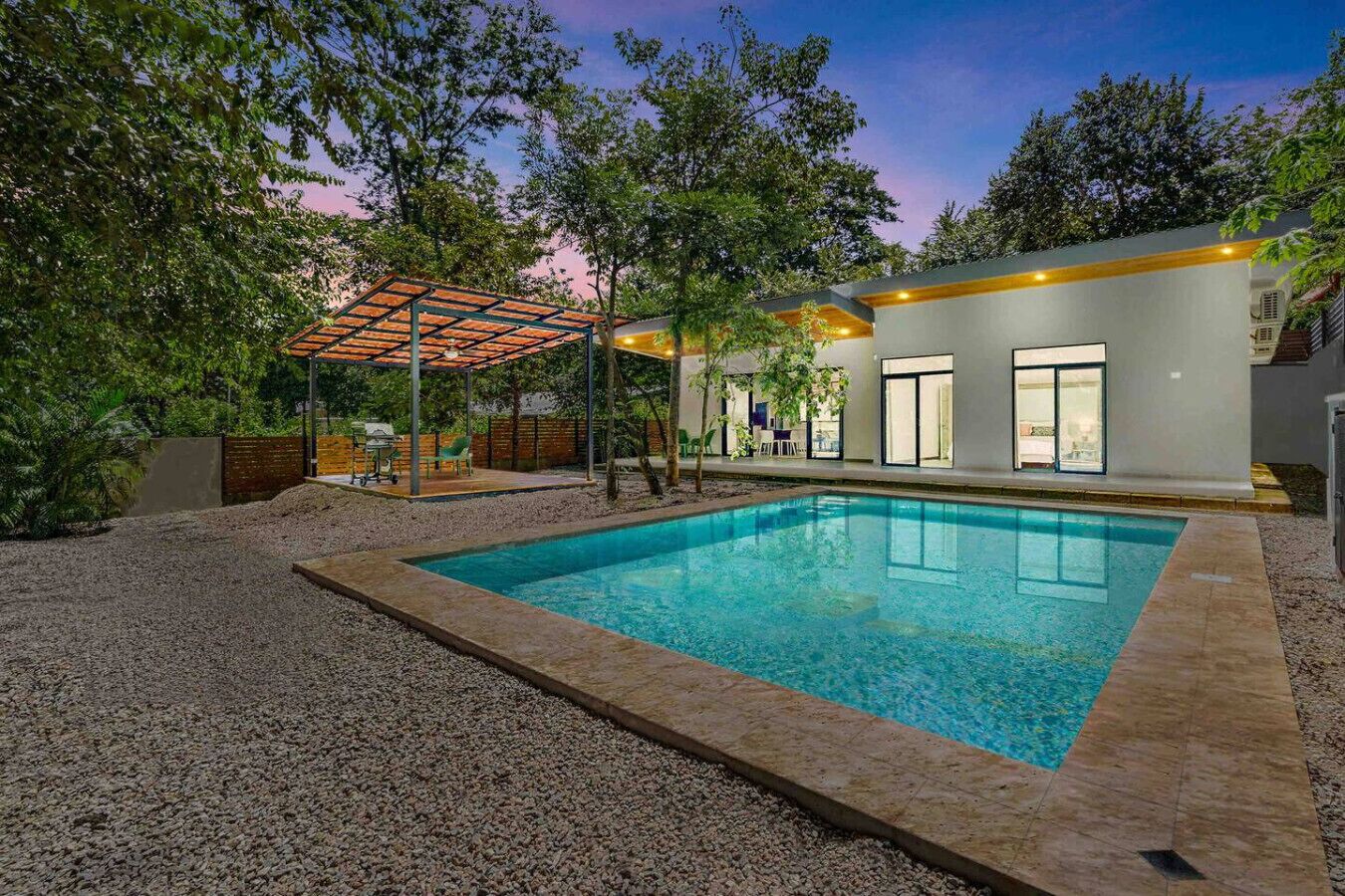 Een modern huis met een zwembad, een overdekt terras en een groot raam met uitzicht op het zwembad.