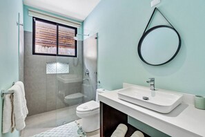 Une salle de bain moderne avec une douche à parois de verre, des toilettes et un lavabo avec un miroir.