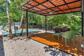 A covered outdoor area with a pool, wooden deck, and seating. - Home with the best pool 5 min drive to town (tamarindo)