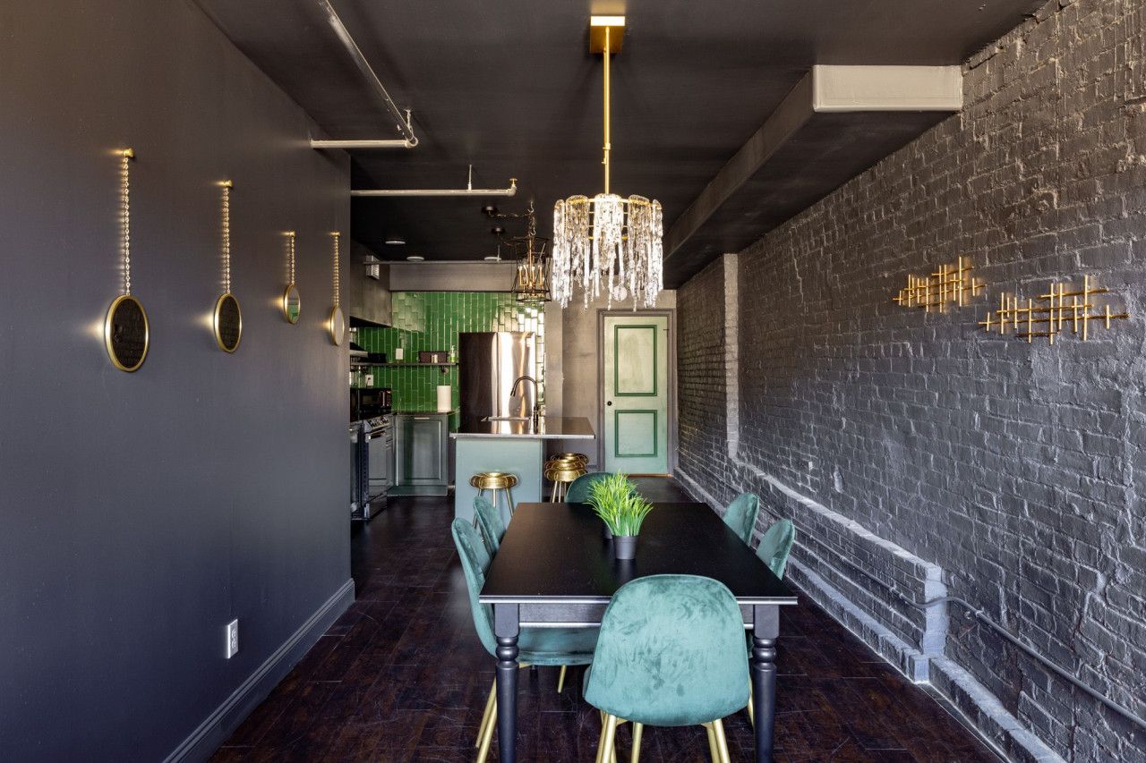 A modern dining area with a black table, green chairs, and a chandelier.