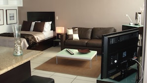 A hotel room with a bed, a sofa, a coffee table, a TV, and a ceiling fan. - Central located luxury studio, steps to all bars & restaurants,  (Puerto Vallarta)