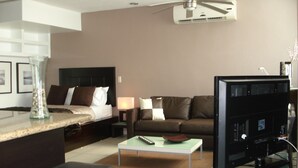 A modern hotel room with a bed, a sofa, a coffee table, a TV, and a ceiling fan. - Central located luxury studio, steps to all bars & restaurants,  (Puerto Vallarta)