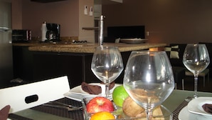 A dining table with wine glasses, plates, and fruits. A kitchen is visible in the background. - Central located luxury studio, steps to all bars & restaurants,  (Puerto Vallarta)